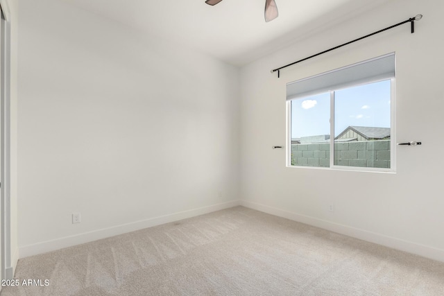 carpeted empty room with baseboards and a ceiling fan