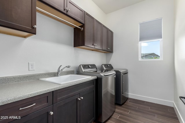 laundry area featuring a sink, washing machine and clothes dryer, baseboards, cabinet space, and dark wood-style flooring