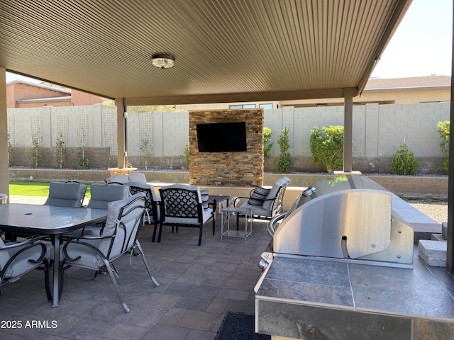 view of patio with a fenced backyard, an outdoor stone fireplace, area for grilling, and outdoor dining space