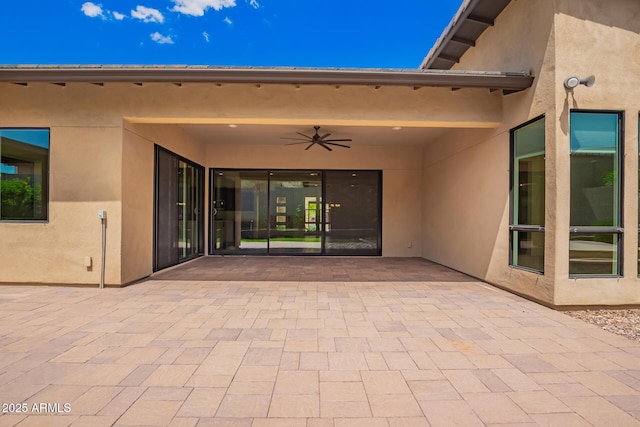 doorway to property with stucco siding, a patio area, and ceiling fan