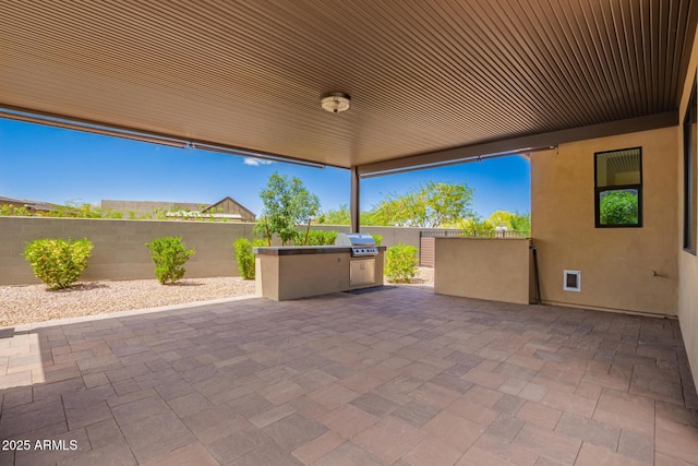 view of patio featuring fence, exterior kitchen, and area for grilling