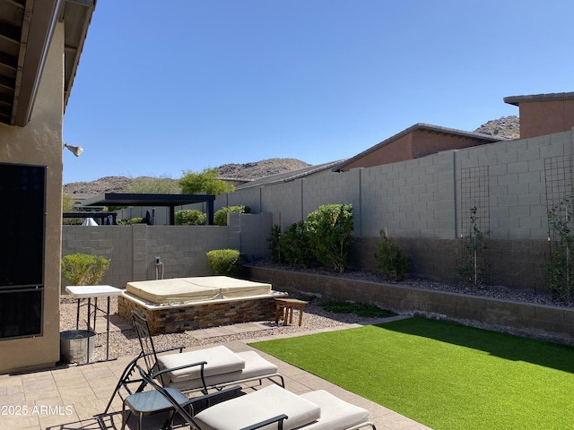 view of yard with a mountain view, a covered hot tub, a fenced backyard, and a patio area
