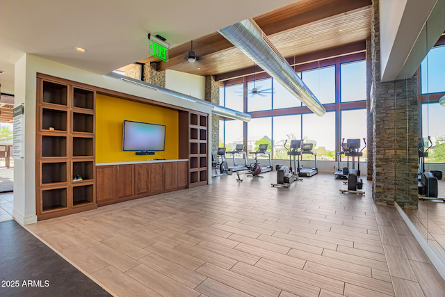 workout area with wood finished floors, expansive windows, a high ceiling, and ceiling fan