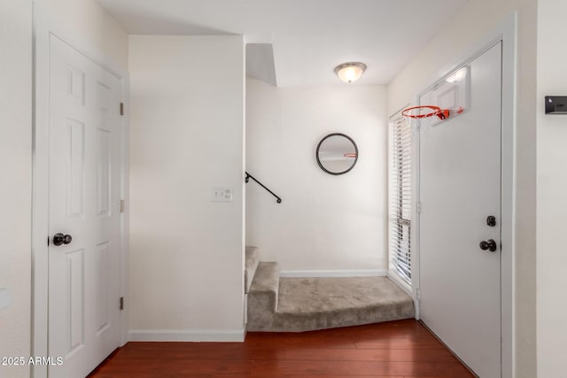 foyer entrance featuring dark wood-style flooring, stairway, and baseboards