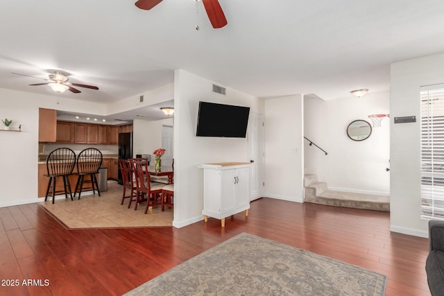 living area with dark wood-style floors, visible vents, baseboards, and stairs