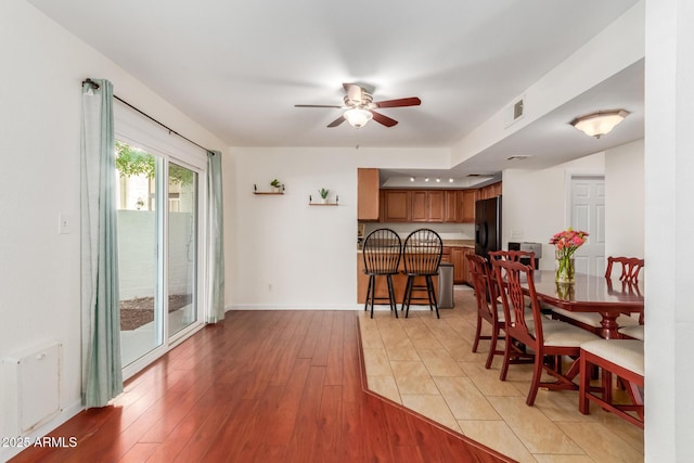 dining area with light wood finished floors, ceiling fan, visible vents, and baseboards