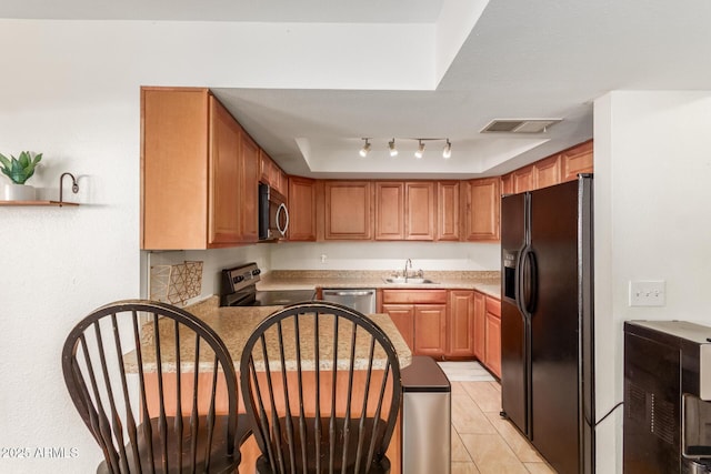 kitchen with visible vents, a raised ceiling, appliances with stainless steel finishes, light countertops, and a sink