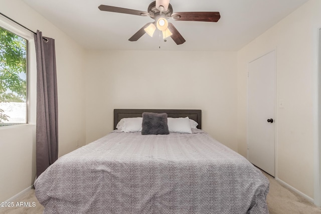 bedroom with a ceiling fan, light carpet, and baseboards