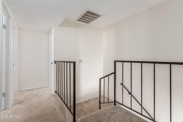 hall featuring light colored carpet, visible vents, and baseboards