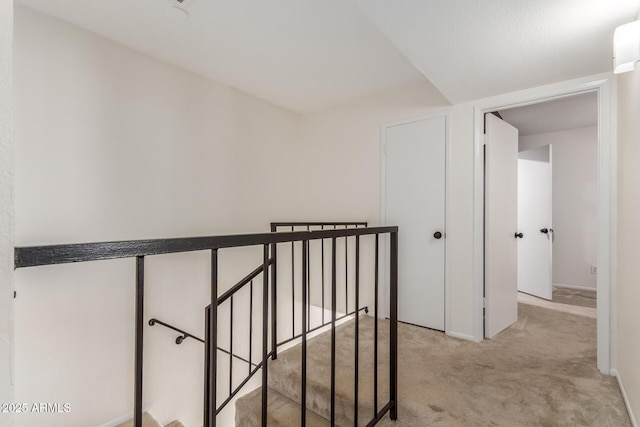 hallway with light colored carpet and an upstairs landing