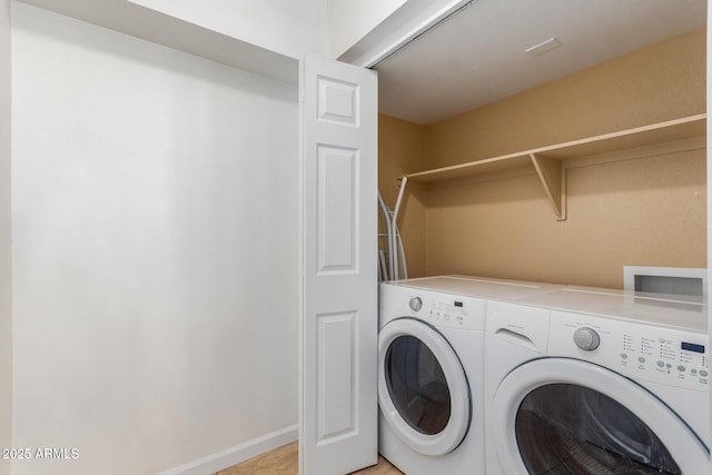 clothes washing area with laundry area, separate washer and dryer, and baseboards