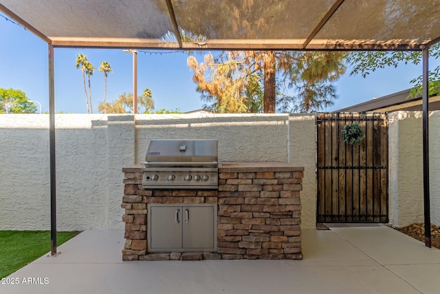 view of patio with an outdoor kitchen, area for grilling, and a gate