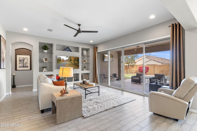 living room featuring ceiling fan and built in shelves