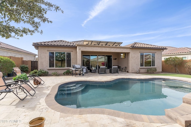 rear view of property with a fenced in pool and a patio area