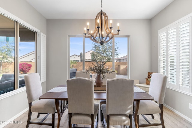 dining area with a wealth of natural light, light hardwood / wood-style floors, and a chandelier