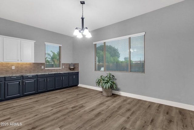 interior space with light wood-style floors, white cabinets, a chandelier, and tasteful backsplash