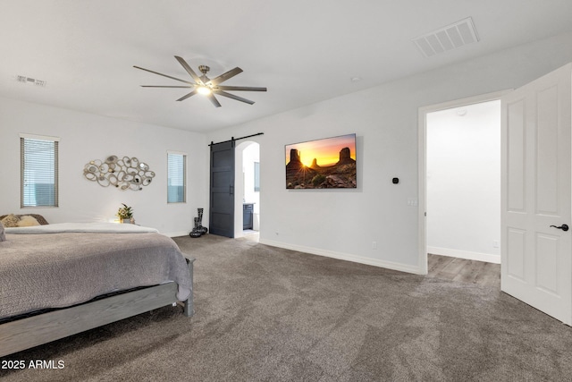 carpeted bedroom with baseboards, visible vents, a barn door, and multiple windows