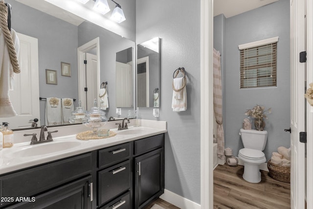 bathroom with double vanity, a sink, wood finished floors, and toilet