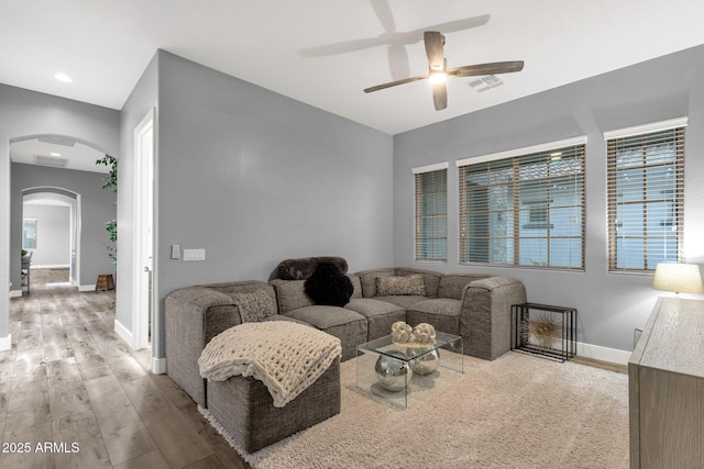 living room with ceiling fan, arched walkways, baseboards, wood finished floors, and visible vents