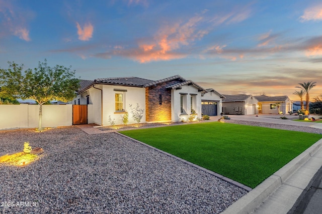 view of front facade featuring fence, a garage, a tiled roof, a yard, and driveway