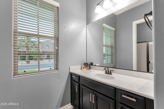 bathroom featuring plenty of natural light, a textured wall, and vanity