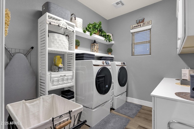washroom featuring visible vents, cabinet space, baseboards, light wood-style floors, and washer and clothes dryer