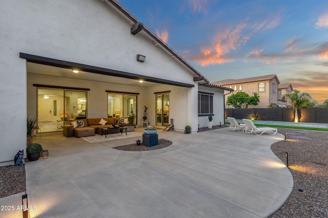 rear view of house with fence, outdoor lounge area, a patio area, and stucco siding