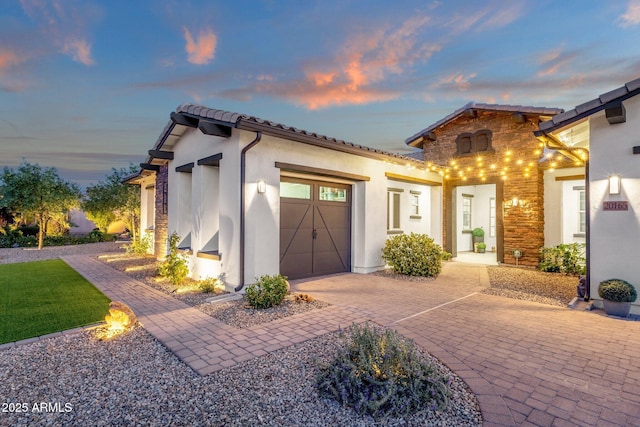 view of front of property featuring decorative driveway, a garage, and stucco siding