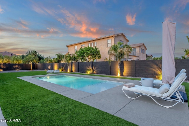 pool at dusk with a yard, a patio, a fenced in pool, and a fenced backyard