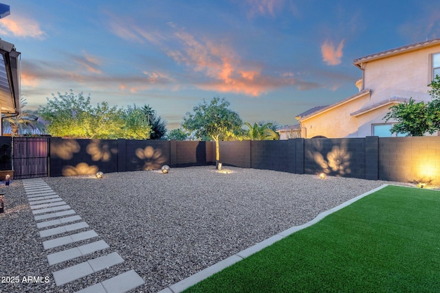 yard at dusk with a fenced backyard and a gate