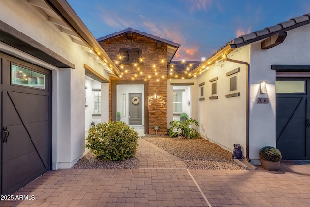 view of exterior entry featuring stucco siding and stone siding