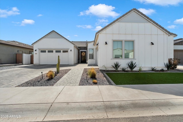 modern farmhouse style home with a garage, board and batten siding, fence, and decorative driveway