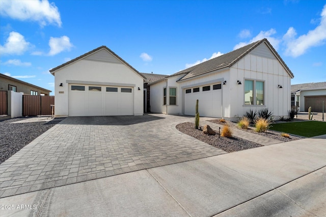 view of front facade featuring decorative driveway, fence, and an attached garage