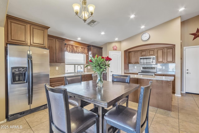 dining room with a notable chandelier, light tile patterned floors, sink, and lofted ceiling