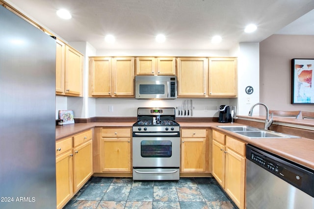 kitchen with light brown cabinets, stainless steel appliances, a sink, and recessed lighting