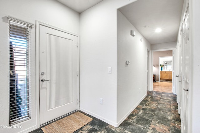 foyer with stone finish flooring and baseboards