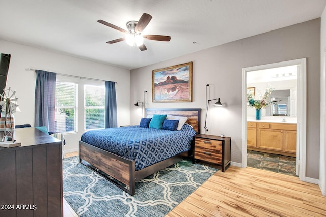 bedroom featuring ensuite bathroom, light wood finished floors, a ceiling fan, and baseboards