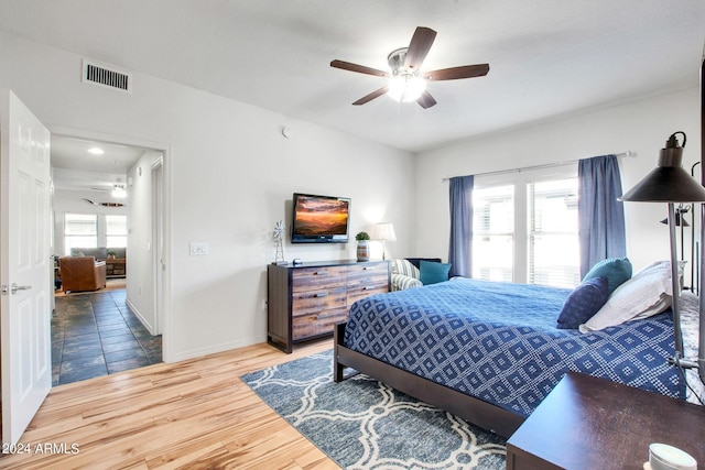 bedroom featuring visible vents, ceiling fan, baseboards, and wood finished floors