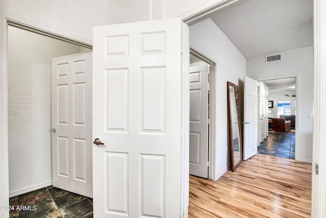 corridor with wood finished floors, visible vents, and baseboards