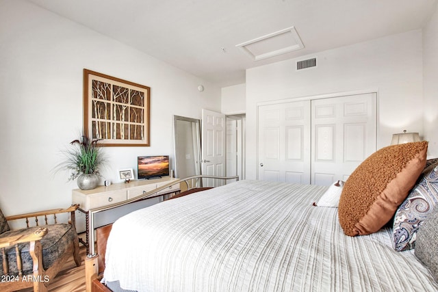 bedroom with a closet, wood finished floors, visible vents, and attic access