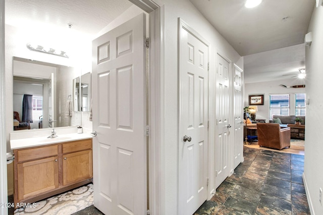 bathroom with stone finish flooring, connected bathroom, and vanity