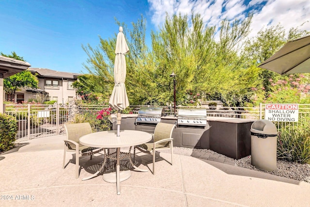 view of patio featuring a grill, fence, outdoor dining area, and exterior kitchen