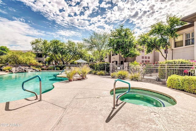 community pool with an in ground hot tub, a patio, and fence