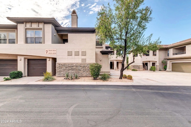 view of front of home featuring driveway, stone siding, an attached garage, and stucco siding