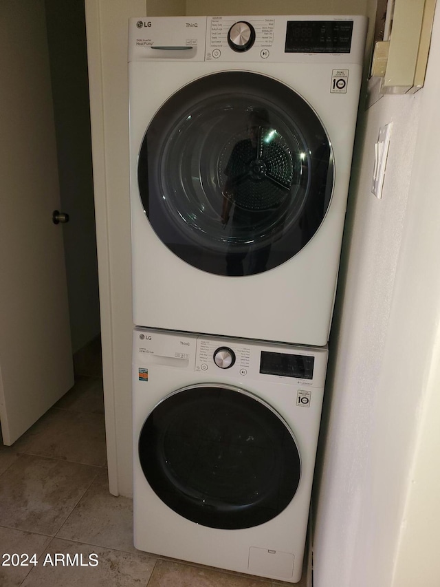 laundry room with stacked washer and dryer and light tile patterned floors