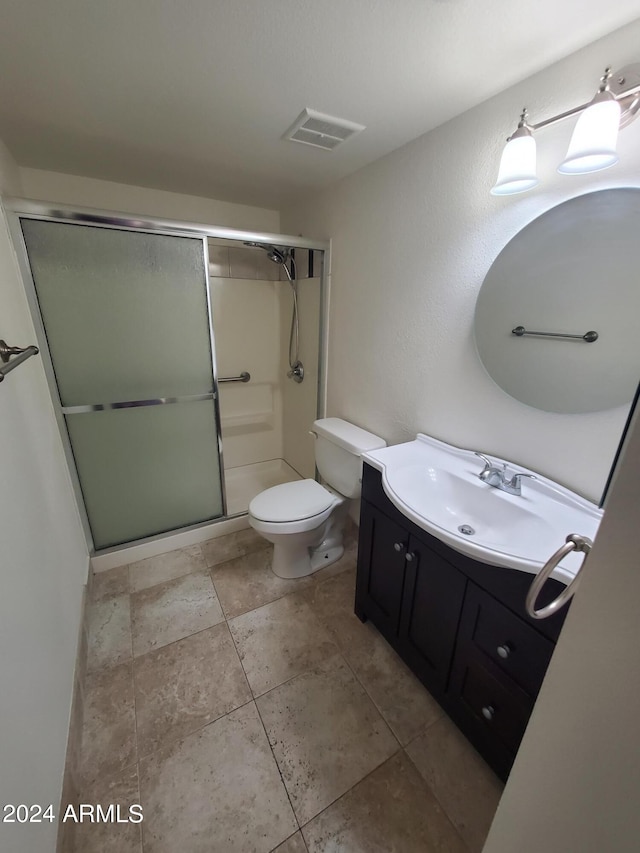 bathroom featuring vanity, toilet, tile patterned floors, and an enclosed shower