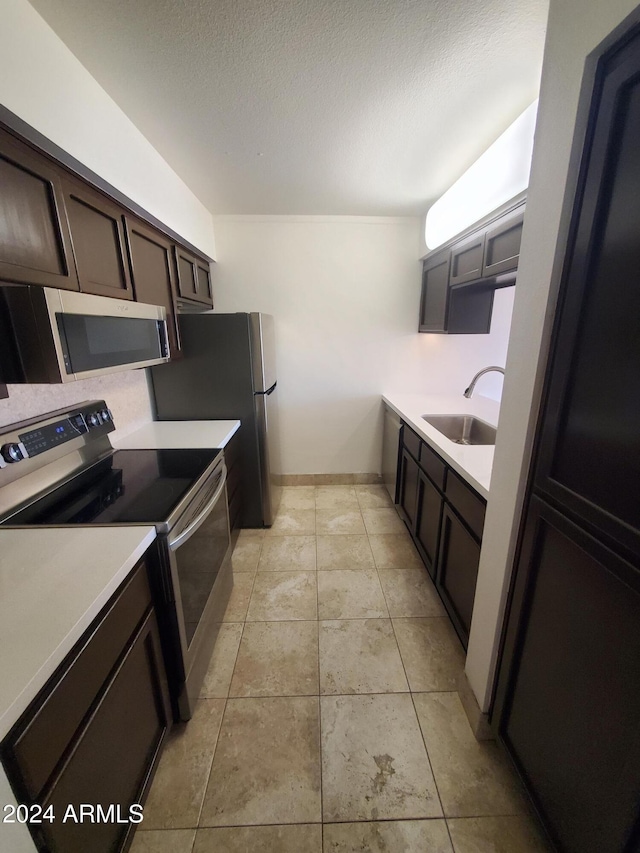 kitchen featuring sink, dark brown cabinetry, stainless steel appliances, and a textured ceiling