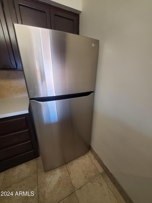 interior space with stainless steel fridge, dark brown cabinetry, and light tile patterned floors