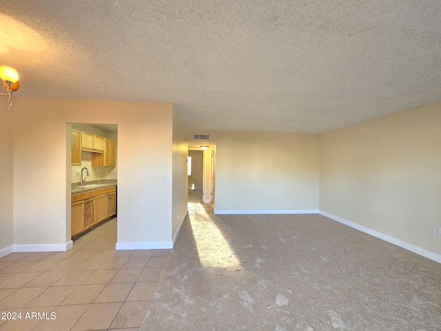 unfurnished living room with light tile patterned flooring, a textured ceiling, and sink