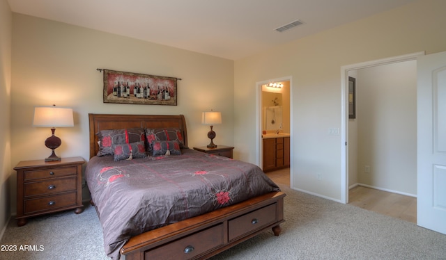 bedroom with sink, light carpet, and ensuite bath